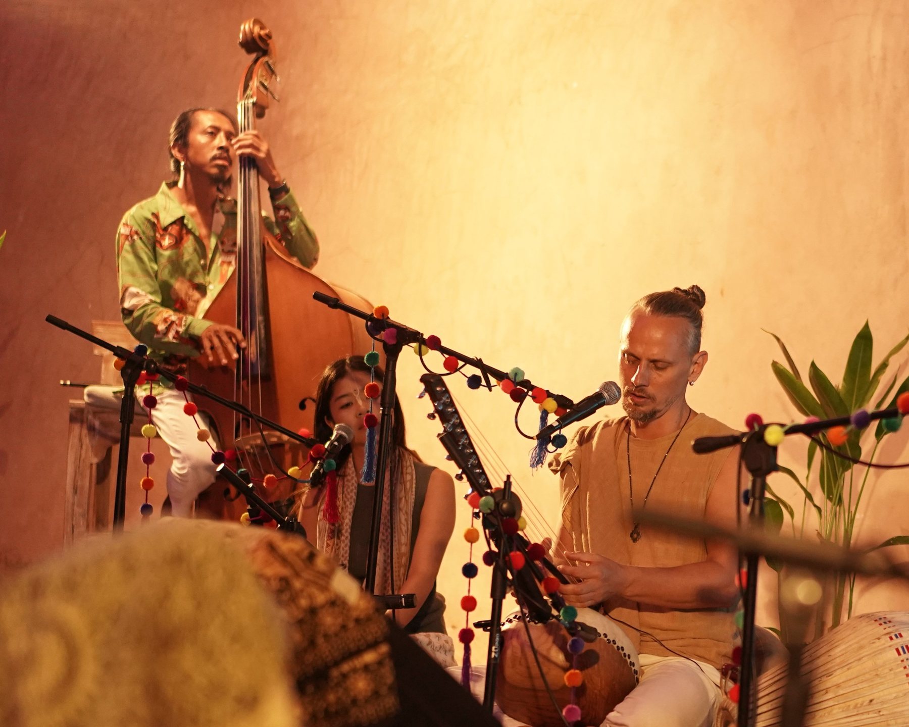 Acharya singing and playing kora with double bass and vocals, warm candlelit stage